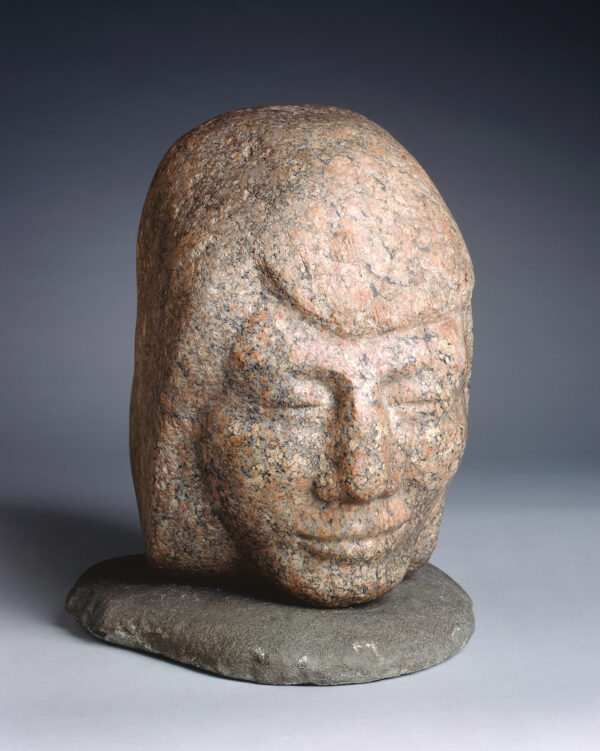 A head of a woman rests on another flat stone.