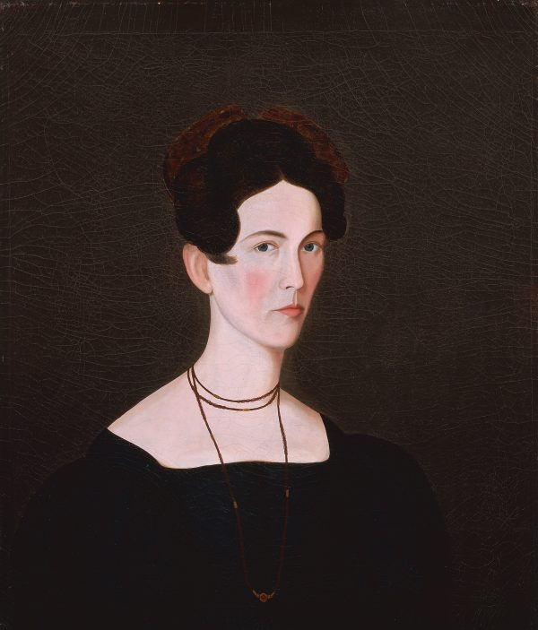 A formal portrait of a woman in a dark dress complimented by a necklace.