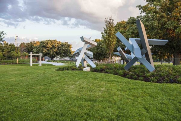 Photo of two large metal sculptures surrounded by green grass and green bushes