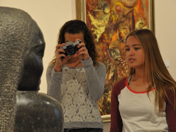 Interior view of two high schools girls photographing a sculpture