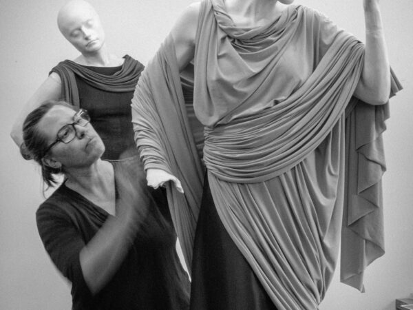 Photo of woman wearing glasses working with mannequins draped in fabric