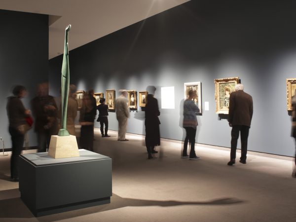 Interior view of galleries with adults looking at artwork on the wall from French Impressionist painters