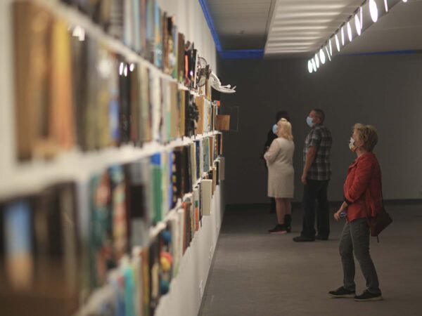 Interior image of the Foot in the Door galleries with multiple visitors looking at paintings on the wall