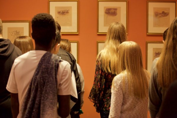 Interior view of a group of students looking at prints on the wall