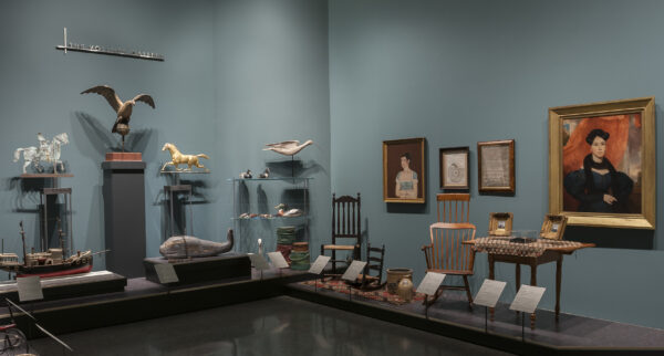 Interior image of galleries showing WAM’s Americana collection of decorative arts with two portraits on the wall, two wooden chairs, a rug, two duck decoys, a wooden eagle