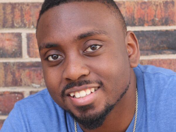 Photo of man in front of brick wall