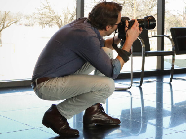 Man crouched down facing his camera off to the right side of the frame
