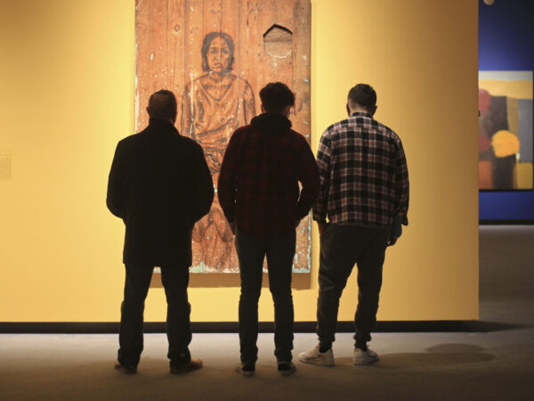 Silhouette of three men in front of painting in the gallery