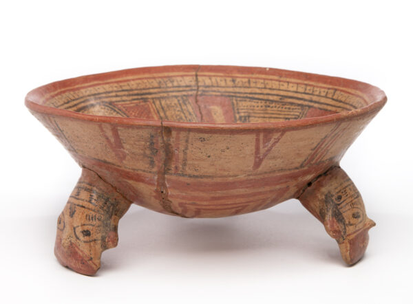 Heads on the tripod legs. This is a rattle bowl. Cream ground with terracotta and black decoration. The design is decorative with dotted lines, hash marks and cross-hatching.