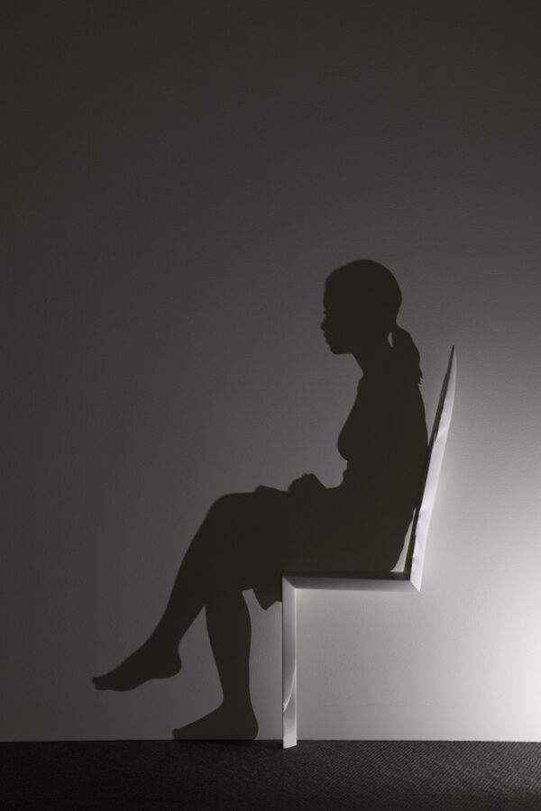 Sculpture of a woman sitting in a chair.