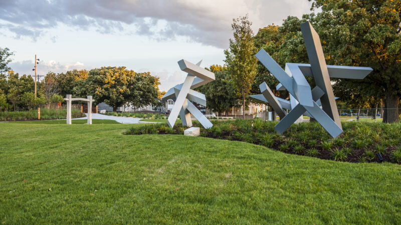 Photo of three sculptures in the Art Garden surrounded by green grass and plantings