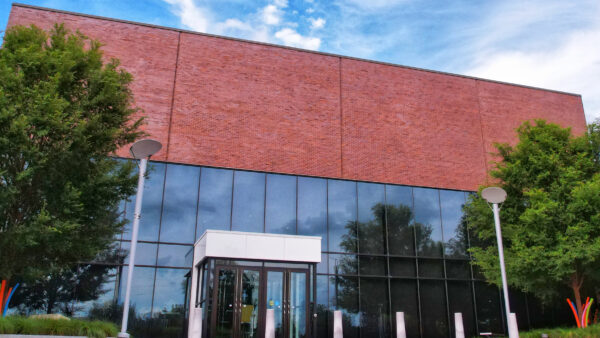 Photo of the museum's glass and brick entrance with trees on either side of the front doors