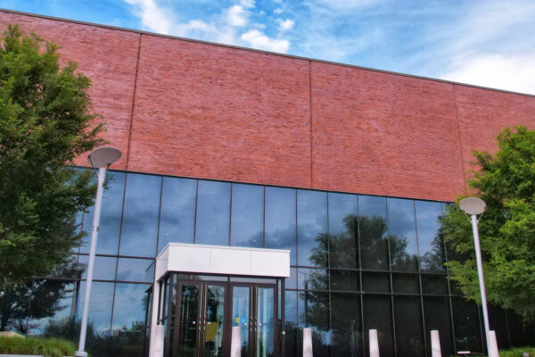 Photo of the museum's glass and brick entrance with trees on either side of the front doors