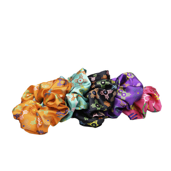 Brightly colored hair ties in a satiny fabric with a multicolor ICT flag motif. From right, orange, turquoise, black, purple, hot pink.