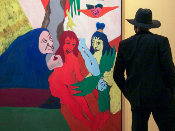 Man in a dark hat and coat stands in front of a large painting in the African American Art in the 20th Century exhibition with his back to the camera