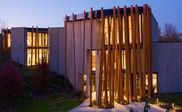 Photo of a concrete building with two dozen three-story wooden beams on the front of floor-to-ceiling windows