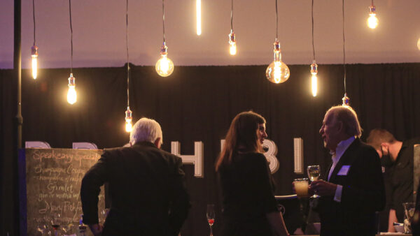 People standing at a bar, with light bulbs suspended from above