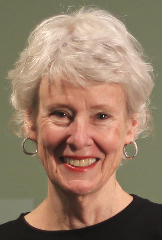 Head and shoulders of a white woman with short white hair, dressed in black jewel-neck
