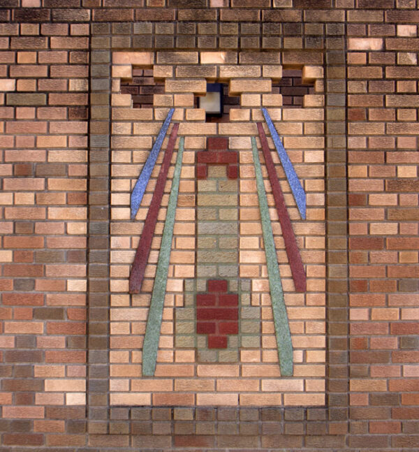 Art Deco relief sculpture on brick wall with geometic shapes suggesting a rocket-shape with stripes in green, red, and blue on either side.