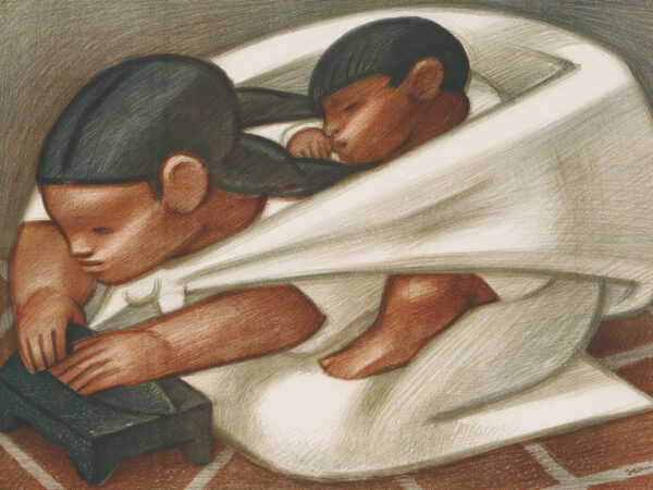 Hispanic woman kneeling on a brick floor kneading dough on a black surface, with a sleeping child on her back in a white sling