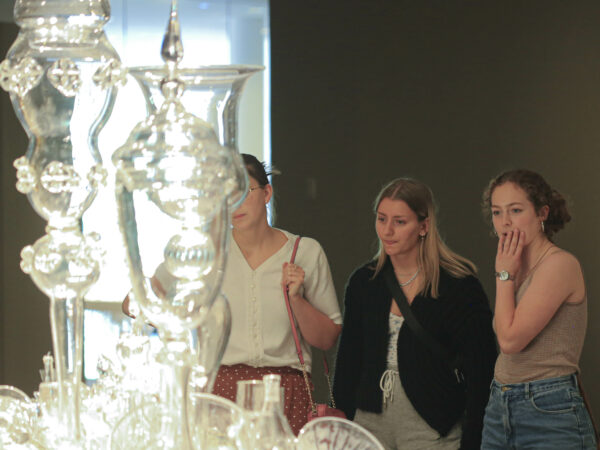 Three young women looking at a glass sculpture