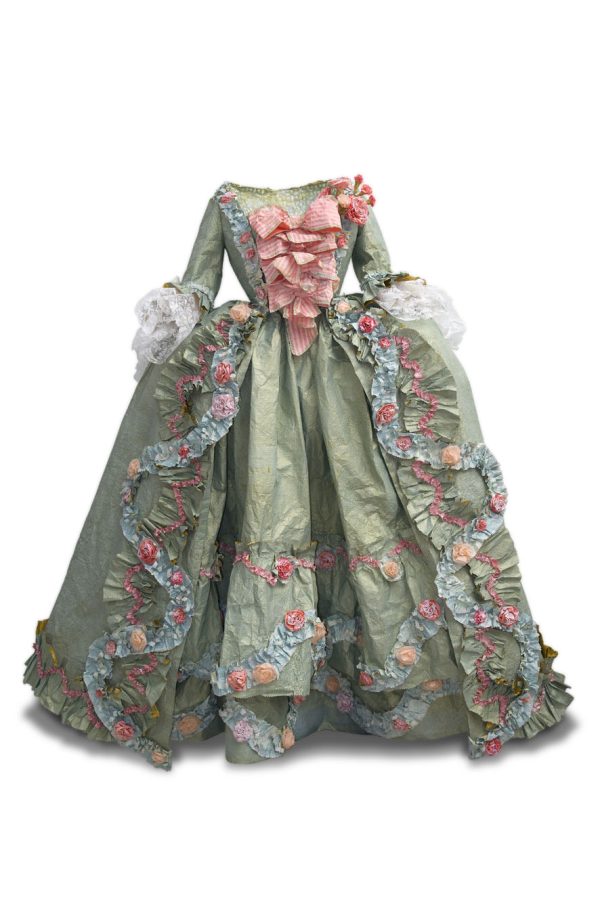 Photo of a paper dress that looks like real fabric in ruffled green with pink floral print. Fitted bodice has a ruffled pink front. Long sleeves end in white ruffled. Full skirt.