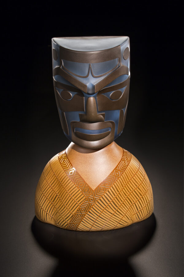 Glass sculpture of a totem-style head in dark brown on a lighter brown base.