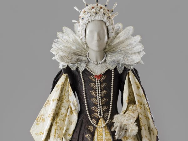 Photo of a life-size woman's royalty dress with an elaborate collar, pearls and a dress of brown and white with gold accents made entirely of paper and painted with acrylic
