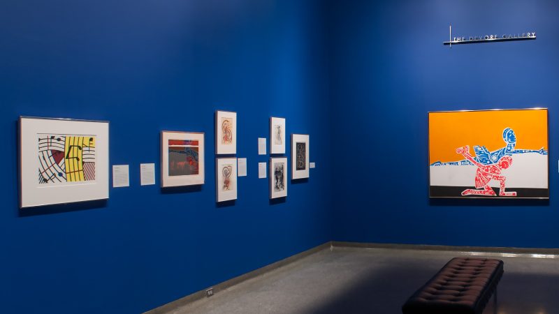 Gallery image with a group of works on a bright blue wall