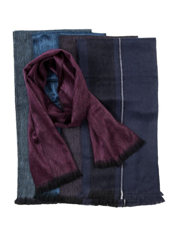Deep red jewel-tone scarf knotted on top of folded cloth in blue tones