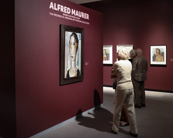 People in a gallery. Text on the wall at left reads Alfred Maurer: American Modern Works on Paper from the Weisman Art Museum Collection. Artwork on the wall is a modernist portrait
