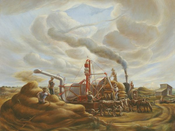 Steam powered threashing machine sends plumes of smoke into a cloudy gray sky