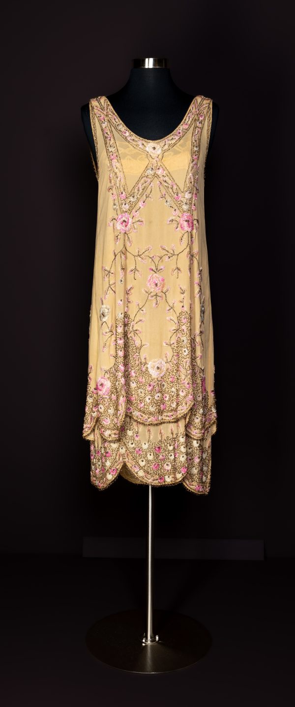 Long, sleeveless gold dress with elaborate beadwork and pink flowers with lace