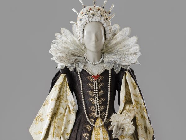 Photo of a life-size woman's royalty dress with an elaborate collar, pearls and a dress of brown and white with gold accents made entirely of paper and painted with acrylic