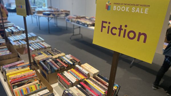 Photo of several tables in the Beren Room filled with gently used books and a Fiction section sign