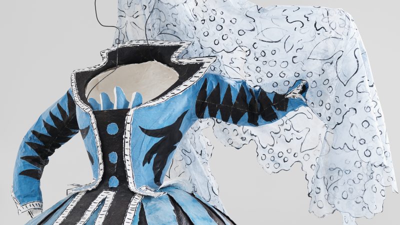 Photo of a paper dress that looks like real fabric in blue and white with black trim and a lace-like shawl