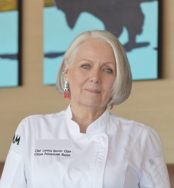 Photograph of a woman with white hair, wearing a white chef's coat.