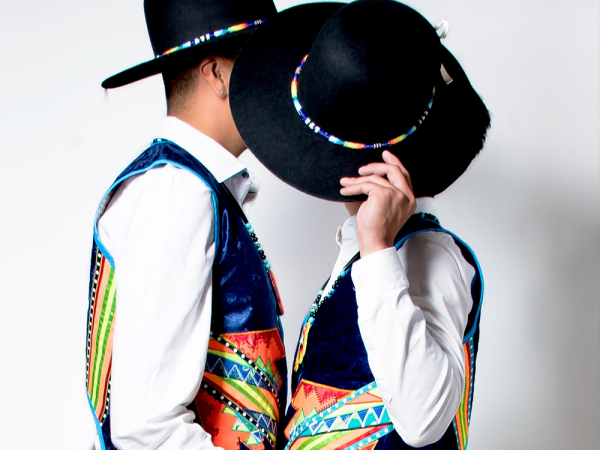 2 male Indigenous dancers. Both faces are covered by one black hat
