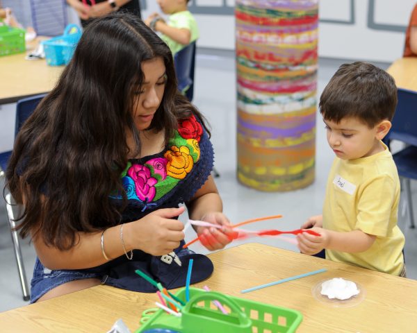 A woman and a toddler doing a craft with colorful pipe cleaners.