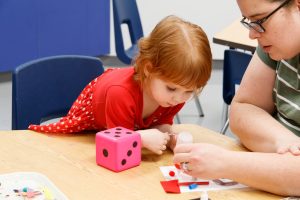 alt= child with parent, creating art piece