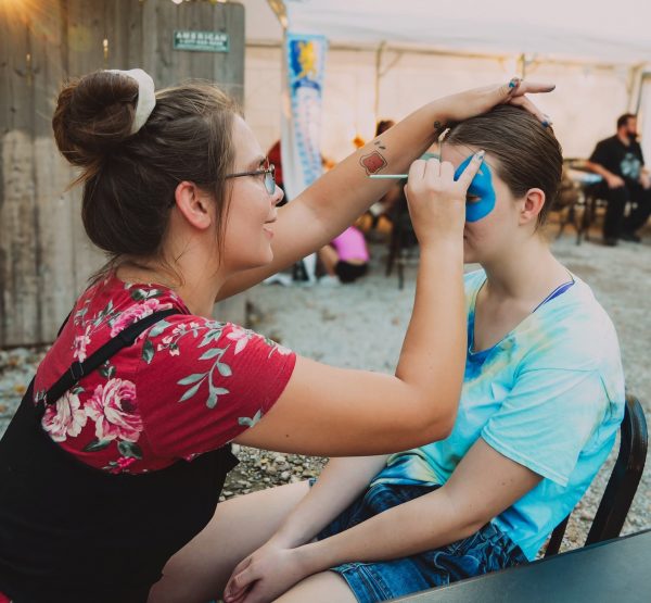 alt= image of artist Samantha Strahler facepainting a child's face